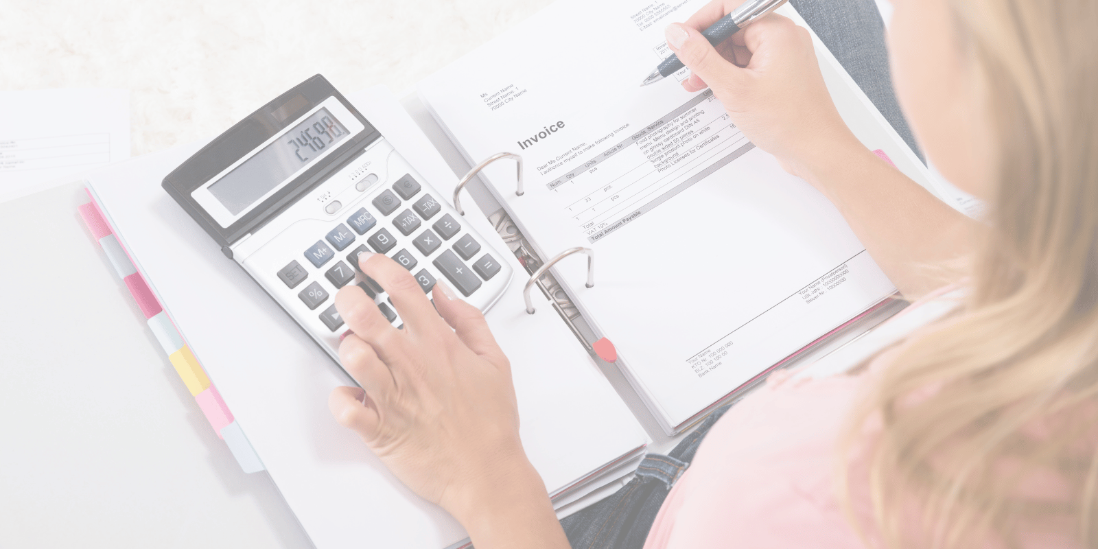 person writing in binder and using calculator