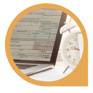 tax form on laptop screen with alarm clock 