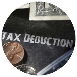 tax deduction written on black background with coins around it 