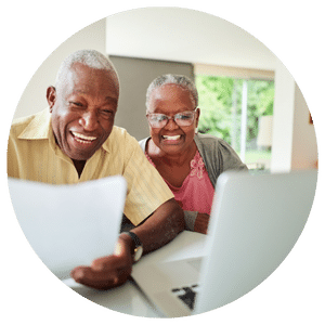 older couple sitting in front of a laptop and holding a piece of paper
