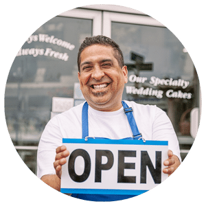 business owner holding open sign in front of store