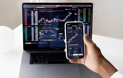 Person evaluating stocks on phone and computer to calculate tax